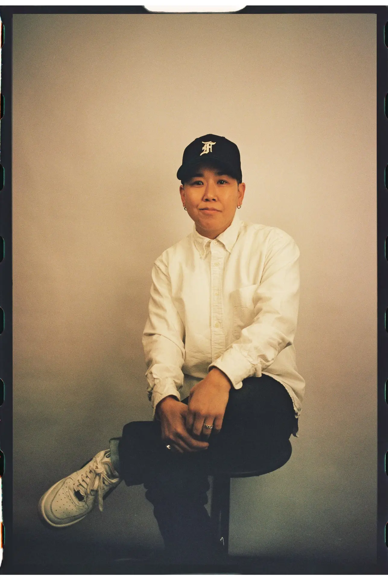 Studio portrait of Jennifer Oh, founder of Mighty Little Studio, seated on a stool