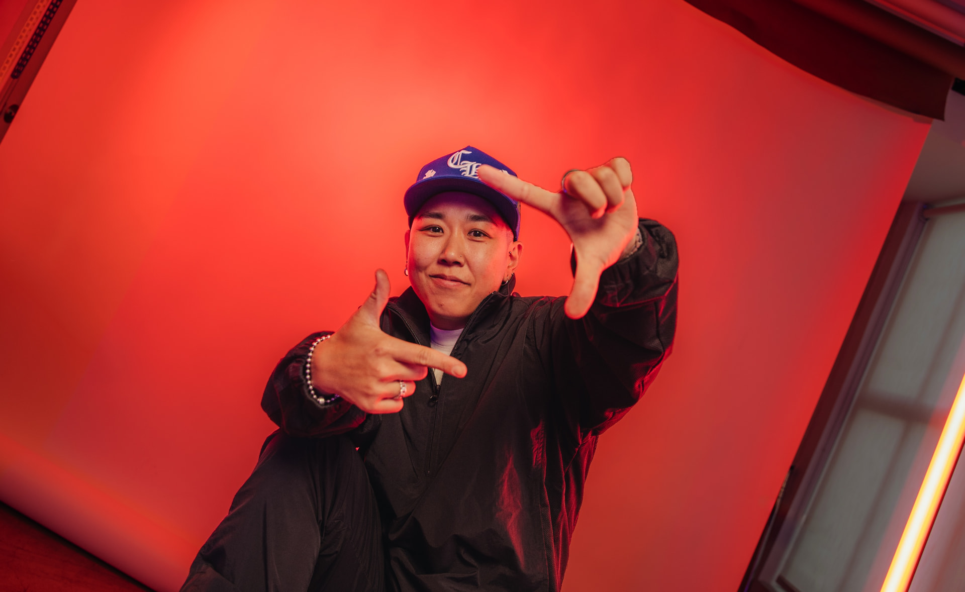 Jennifer Oh framing a shot with her hands against a red-lit backdrop